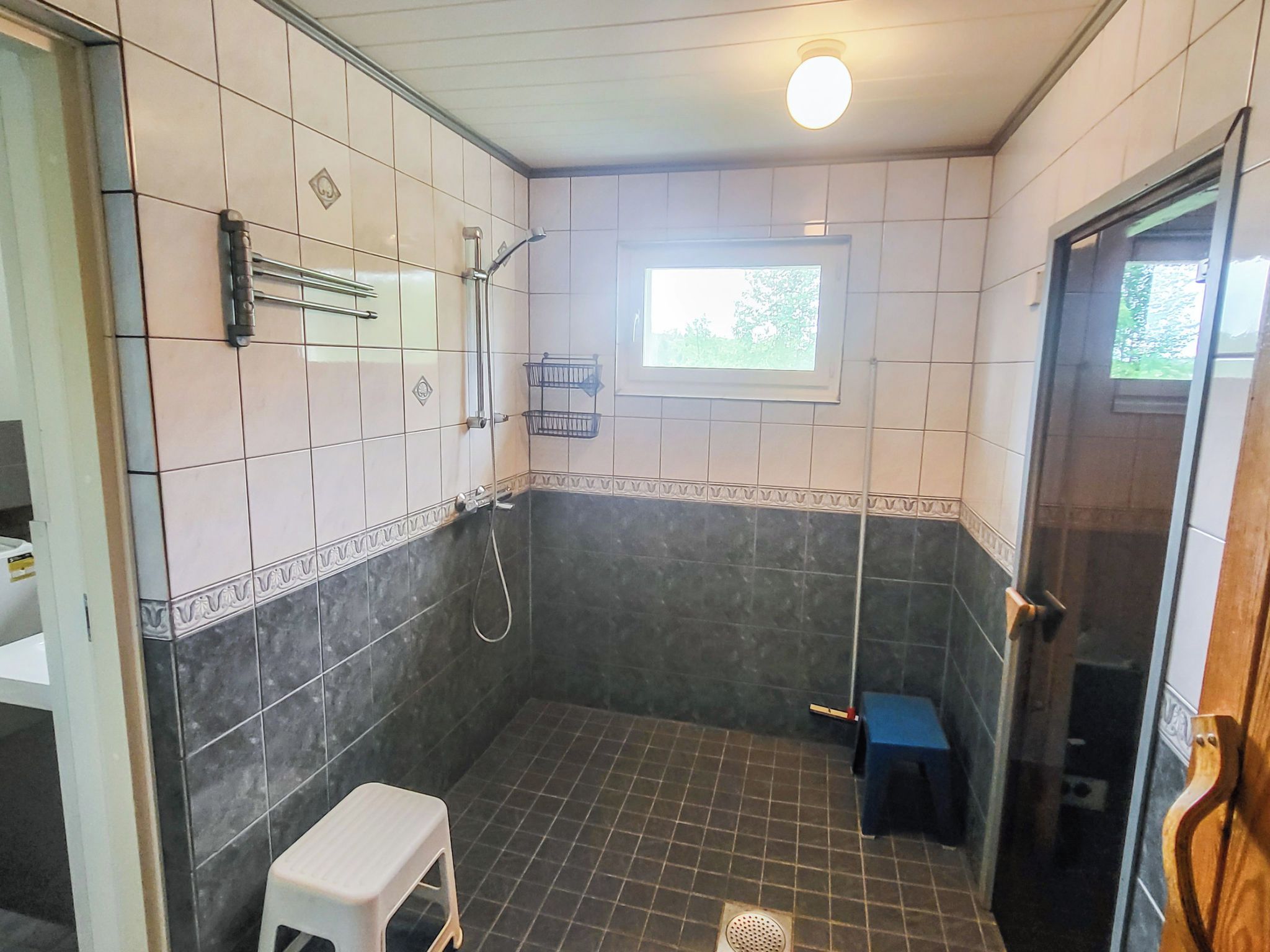 Kylpyhuoneessa on suihku, wc, pieni jakkara ja ikkuna, josta tulee luonnonvaloa.