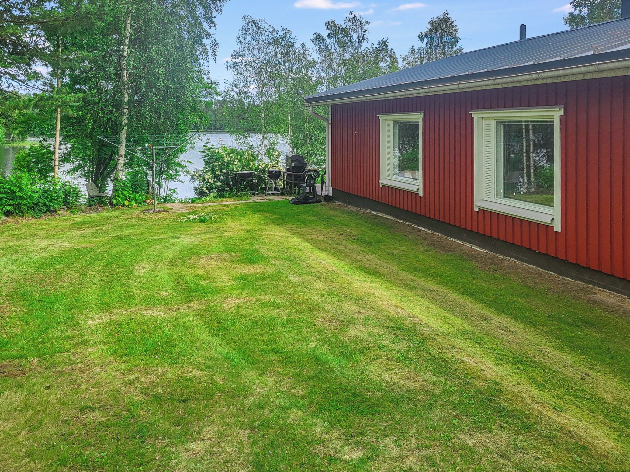 A red building with a well-maintained lawn and a grill area.