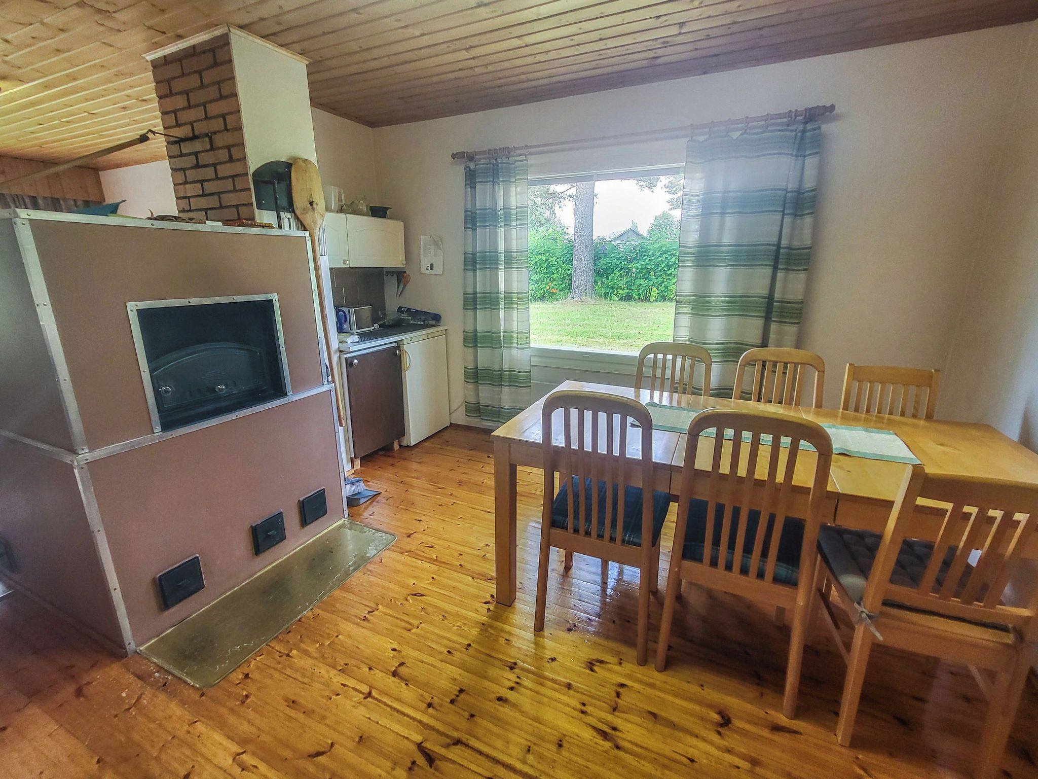 Une cuisine compacte dotée d’un four encastré, d’une table à manger avec des chaises, et offrant une vue sur un paysage verdoyant par la fenêtre.