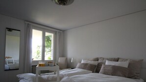 Quarto com cama, mesa de cabeceira, espelho e janela.