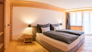 A bedroom with a curved ceiling, a double bed, bedside tables, and a window with curtains. - Les Silenes by Interhome (Gstaad)