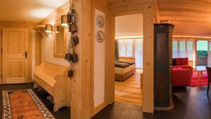 A wooden interior with a bench, a bed, and a red sofa. - Les Silenes by Interhome (Gstaad)