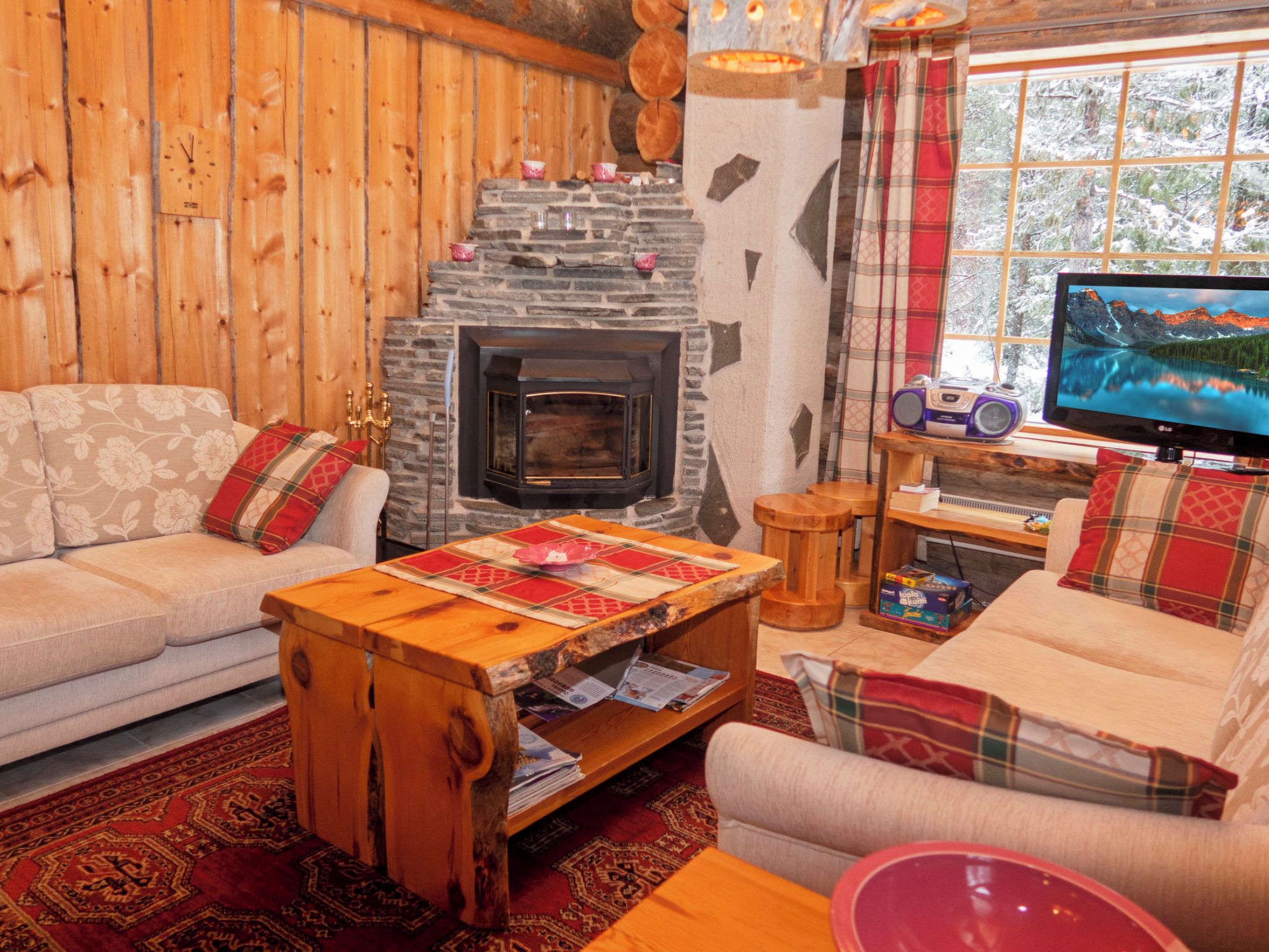 Una sala de estar acogedora con chimenea de piedra, televisor y sofá con cojines escoceses.