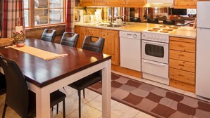 Eine gemütliche Küche mit Holzschränken, einem Esstisch mit Stühlen, einem eingebauten Backofen und einer Mikrowelle.