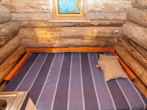 Ein Blockhauszimmer mit einem Bett, einem Fenster und einem kleinen Tisch.
