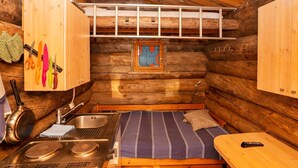 A compact cabin with a bunk bed, a small kitchenette, and a wooden ceiling.