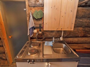 Eine kleine Küche mit Herd, Spüle und Holzschränken.