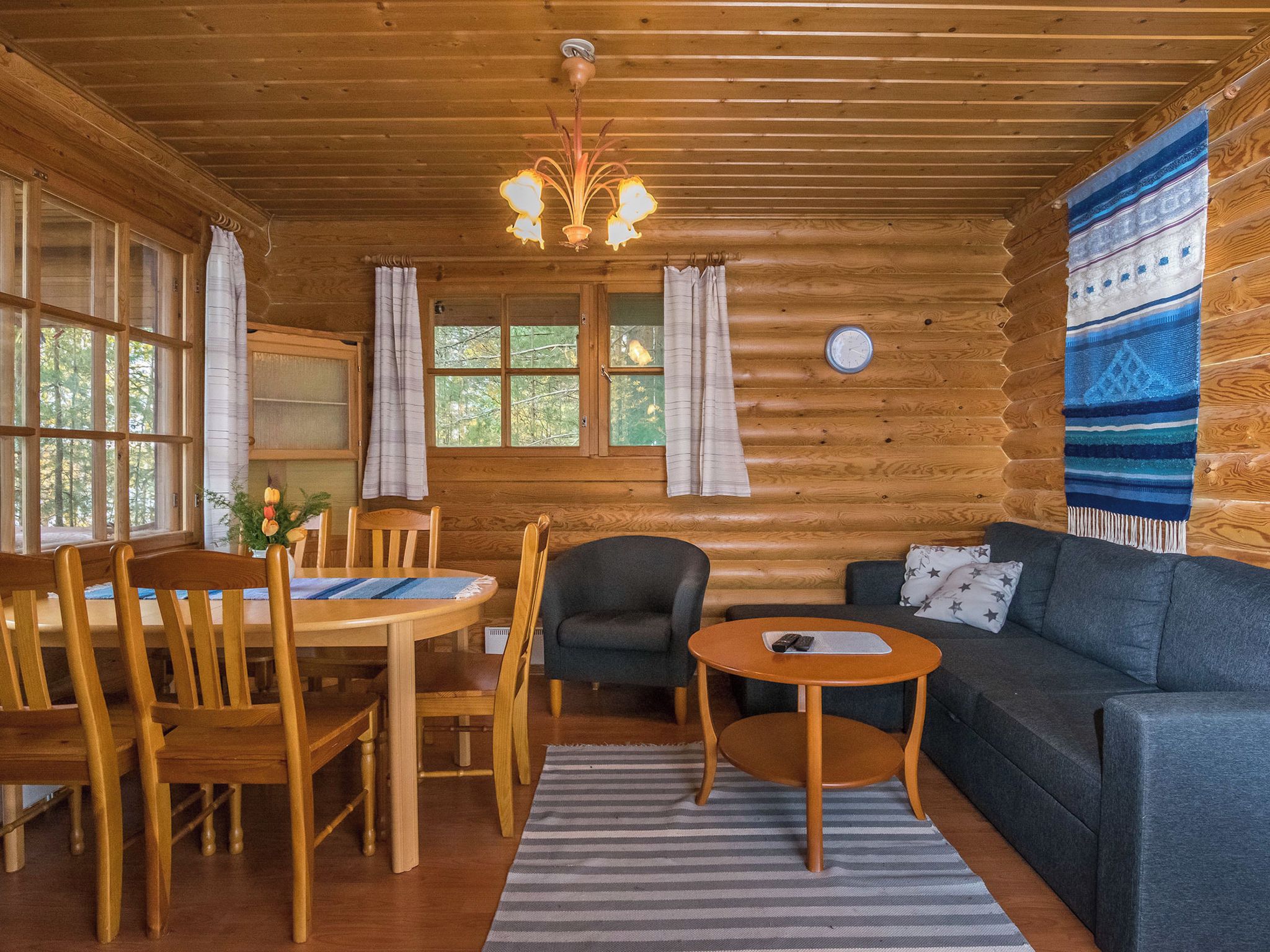 L’intérieur d’une cabane en rondins comprend un coin repas, un canapé et une petite table.