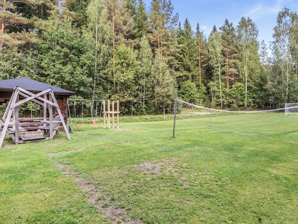 A grassy field with a wooden structure, possibly a gazebo, and a swing set. - Etelärinne by Interhome (Punkaharju)