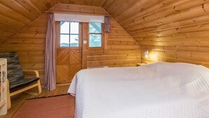 Acogedora habitación tipo cabaña de madera con cama, una silla y una ventana.