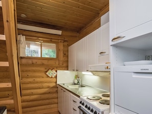 A compact kitchen with wooden walls, a white refrigerator, and a stove. - Etelärinne by Interhome (Punkaharju)