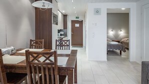 Une chambre d’hôtel moderne dotée d’un coin repas, d’une kitchenette et d’une chambre à coucher séparée.