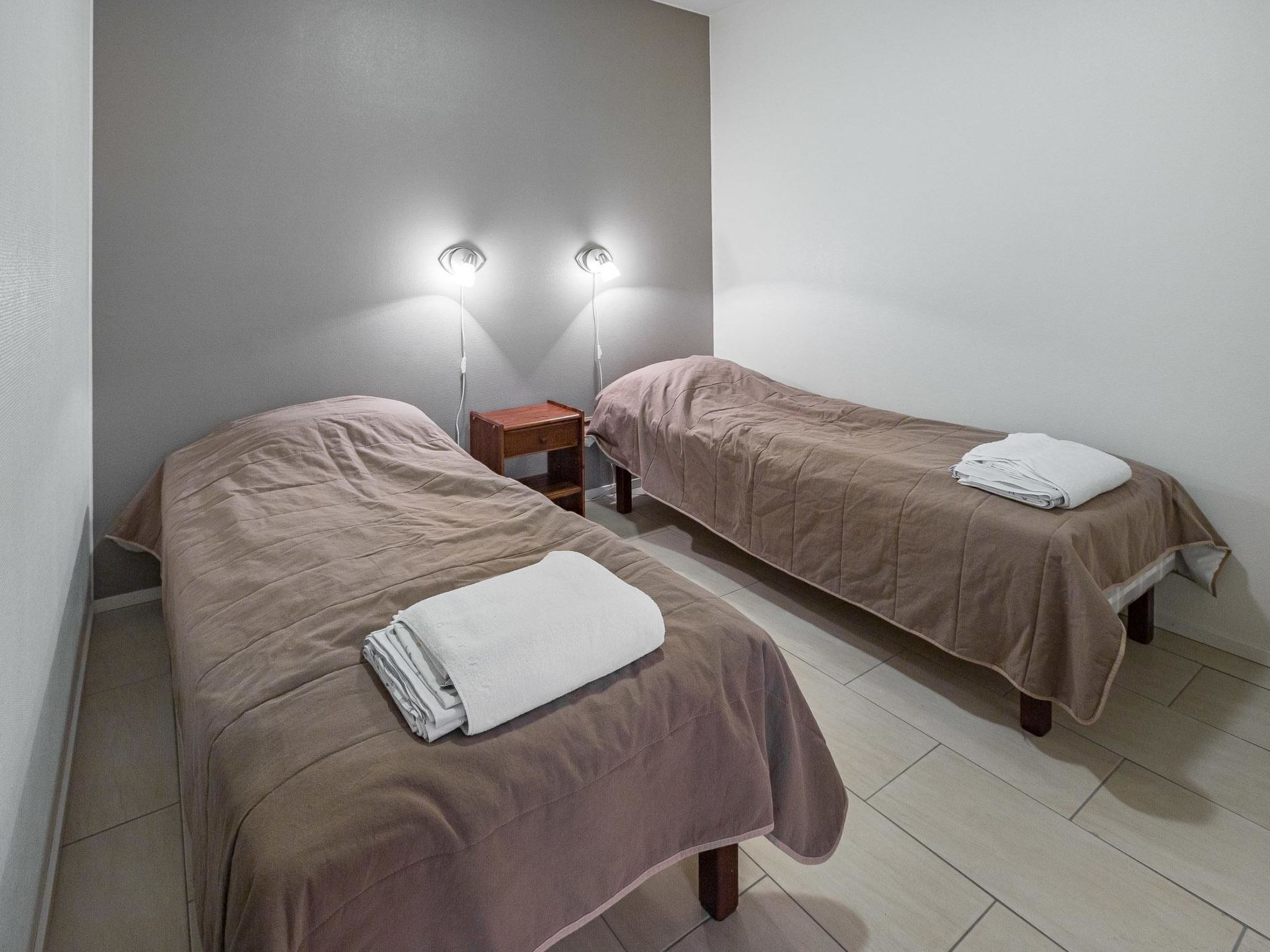 Habitación doble con dos camas, cada una con mesita de noche y lámpara.