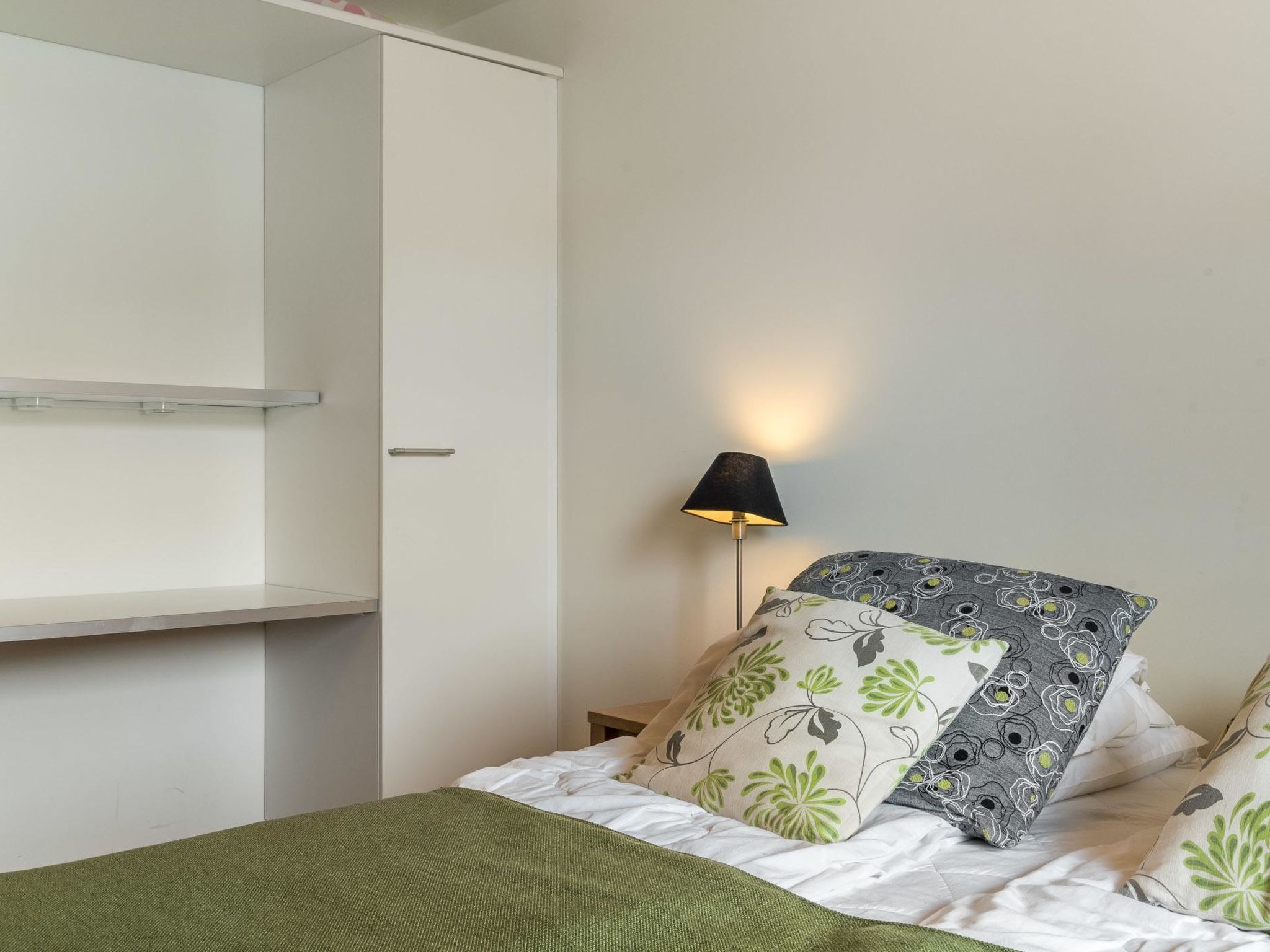 Une chambre à coucher avec un lit, une table de chevet, une lampe et une armoire.