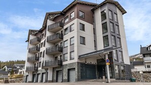 Ein mehrgeschossiges Wohngebäude mit Balkonen, Garagentoren und blauem Himmel.