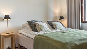 Ein Schlafzimmer mit einem Bett, zwei Nachttischlampen, einem Fenster mit Vorhängen und einer grünen Decke.