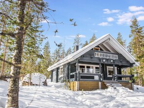 A cabin with a wooden deck, surrounded by snow and trees. - Kalliokoto by Interhome (Puumala)