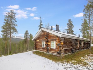 Eine Blockhütte mit Schornstein, Fenstern und verschneitem Grund.