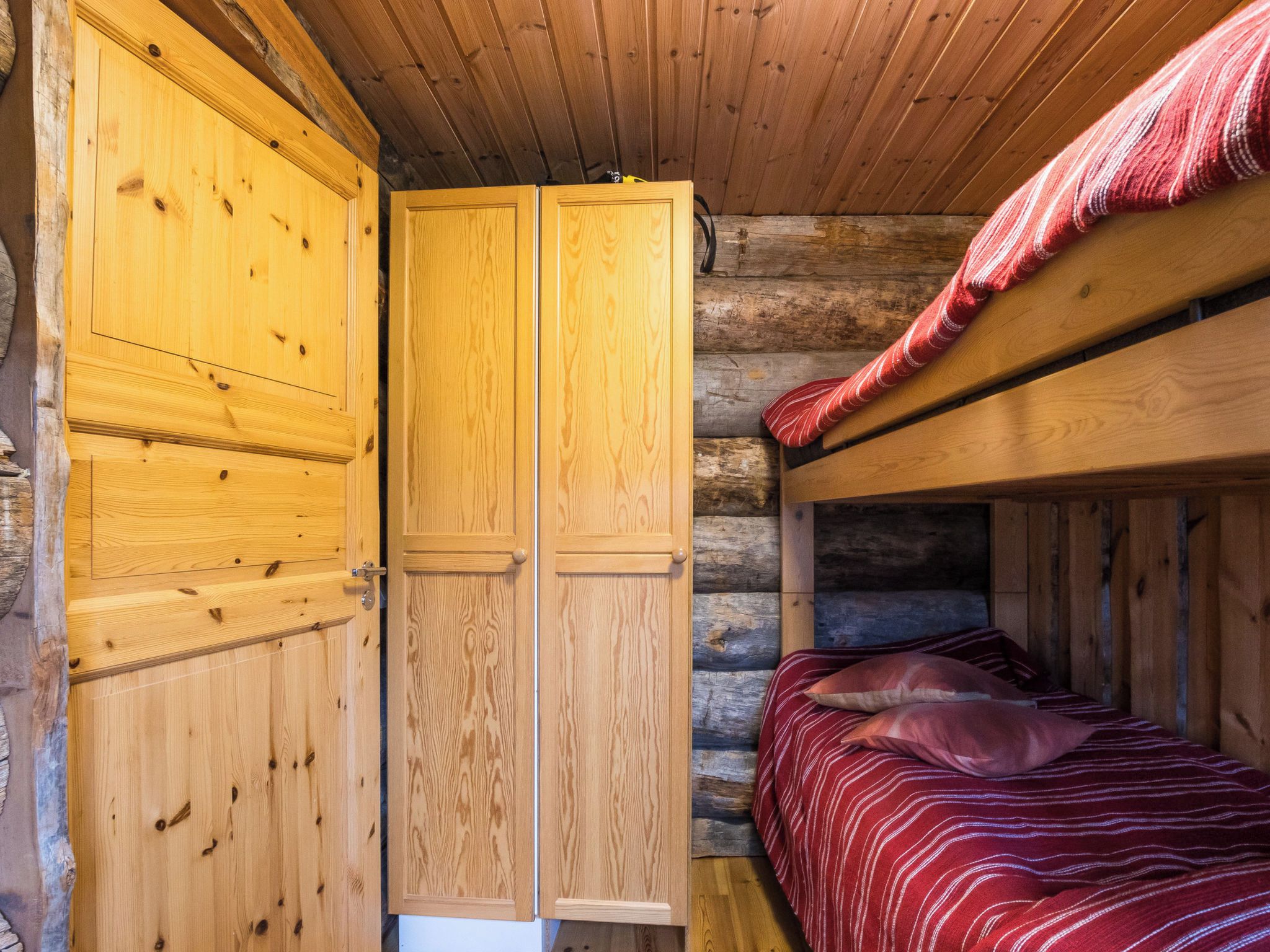 A wooden cabin room with a bunk bed and a wardrobe.