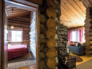 A log cabin interior with a bed, a sofa, and a stone wall. - Lomaylläs d58 /palovaarankaarre 11b by Interhome (Ylläsjärvi)