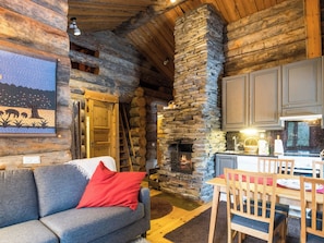 Ein gemütliches Blockhaus-Interieur mit Kamin aus Stein, Holzmöbeln und einem Gemälde an der Wand.