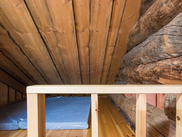 Eine Holzbalkendecke mit geneigtem Design, eine hölzerne Bank und ein blau gemustertes Kissen.