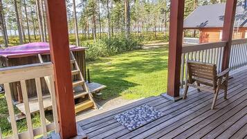 Een houten terras met uitzicht op een gazon en bomen.