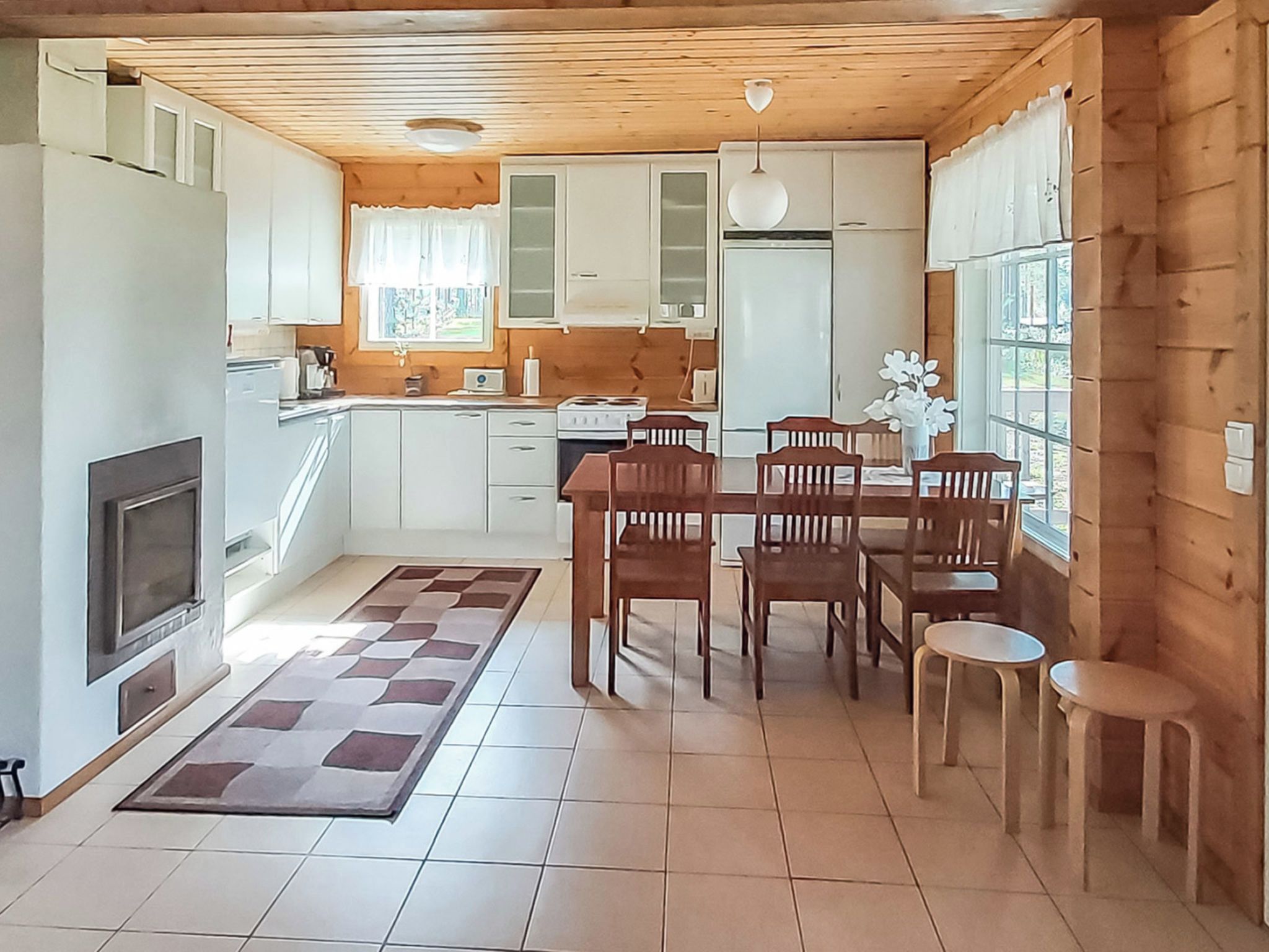 Een kleine keuken met een eethoek, houten plafond en een open haard.
