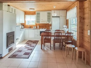 A compact kitchen with a dining area, wooden ceiling, and a fireplace. - Beige 2 by Interhome (Lestijärvi)