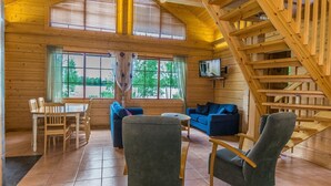 Ein Holzblockhaus-Innenraum mit Essbereich, Sofas und einer Treppe.