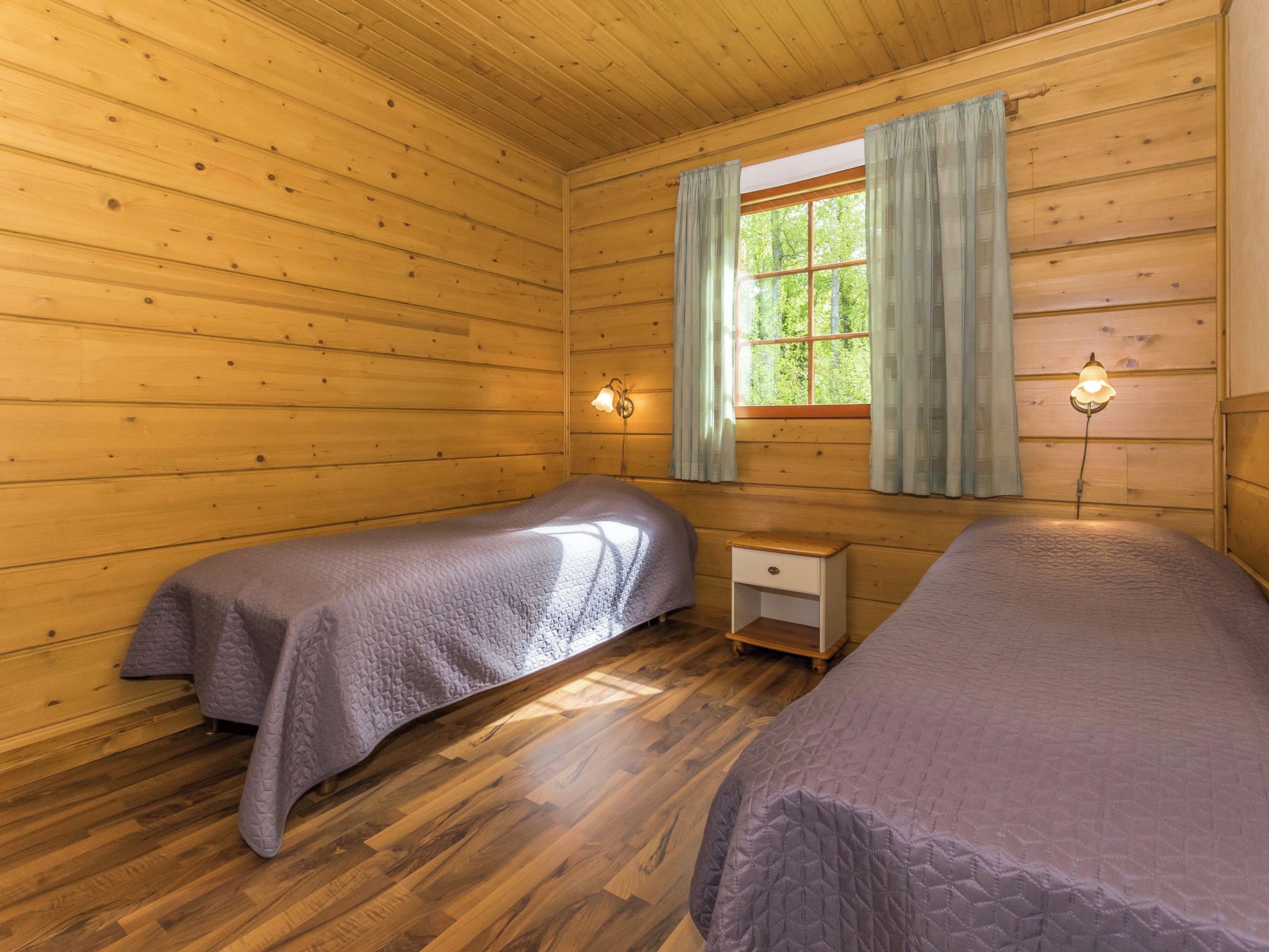 Une cabine équipée de deux lits, d’une fenêtre avec des rideaux et d’une table de chevet avec une lampe.