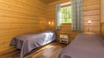 Une cabine équipée de deux lits, d’une fenêtre avec des rideaux et d’une table de chevet avec une lampe.