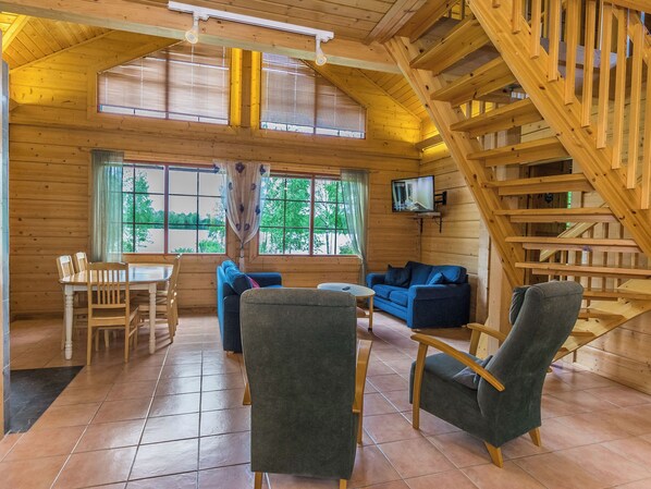 Un intérieur en bois comprenant un coin repas, des canapés et un escalier.