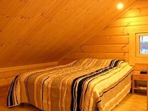 Cozy cabin with a sloped ceiling, featuring a bed, bedside table, and nightstand.