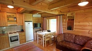 A wooden cabin with a kitchen, dining area, and a sofa. - Rantatupa by Interhome (Ruovesi)