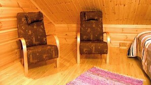 A cabin with two wooden chairs, a wooden ceiling, and a bed with a striped blanket. - Rantatupa by Interhome (Ruovesi)