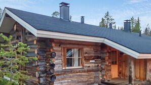 Eine Blockhütte mit einem steilen Dach, einem Schornstein und einer Veranda mit Stufen zum Eingang.
