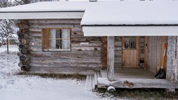 A log cabin with a snow-covered roof and a wooden door.
