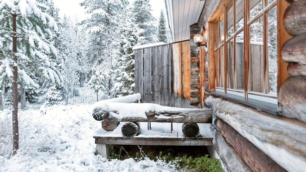 Eine Blockhütte mit einer Holzterrasse und großen Fenstern.