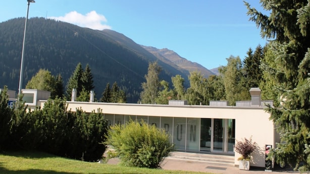Un edificio moderno con techo plano, amplias ventanas y un césped bien cuidado.