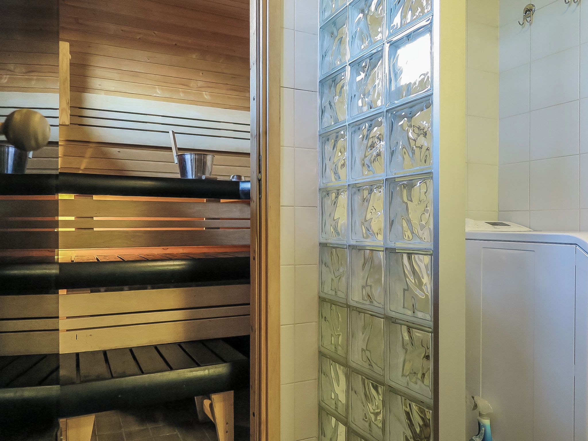 A sauna with a wooden ceiling, a bench, and a glass partition.