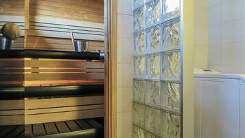 A sauna with a wooden ceiling, a bench, and a glass partition.