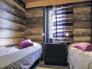 Une cabine comprenant deux lits, une fenêtre avec des rideaux et une table de chevet avec une lampe.