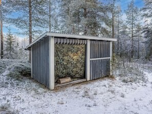 A small, wooden cabin with a camouflage-patterned door, surrounded by a snowy forest. - Pohjaskoti a by Interhome (Kuusamo)