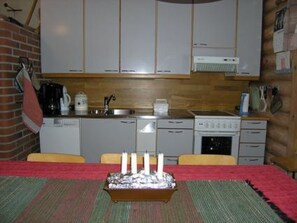 Una cocina compacta con gabinetes blancos, un fogón y un lavabo.