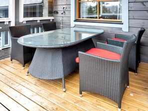 Une table à plateau en verre, accompagnée de quatre chaises, chacune dotée d’un coussin rouge.