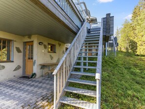 Un escalier en bois mène à un bâtiment doté d’un toit en pente et de détails en pierre.