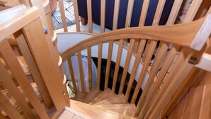 A wooden staircase with a curved handrail, leading to a room with a tiled floor and a white door.