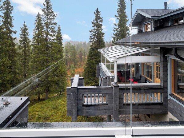 A modern house with a balcony overlooking a forested area.