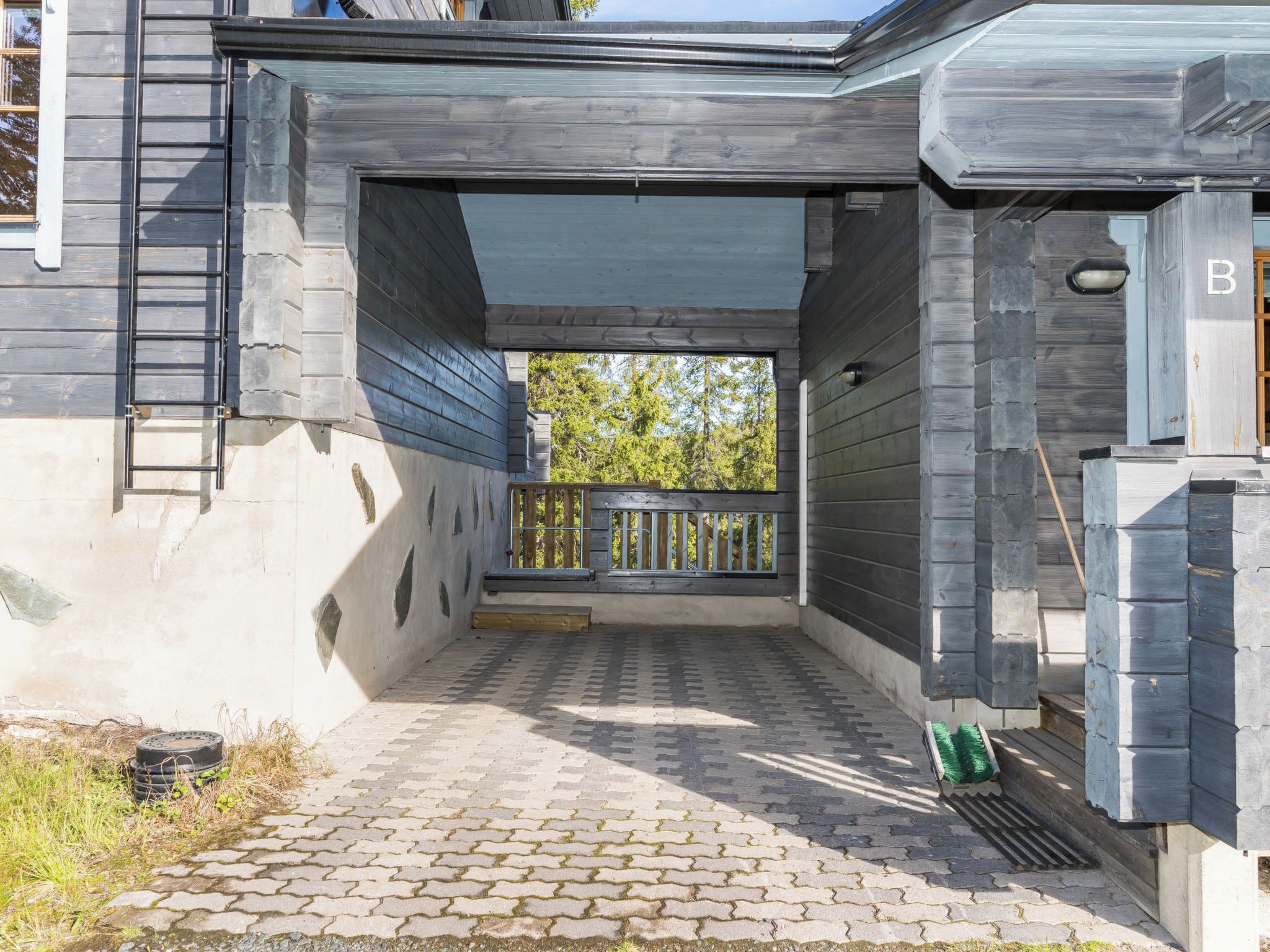 A covered outdoor area with a paved walkway, a wooden railing, and a stone wall.